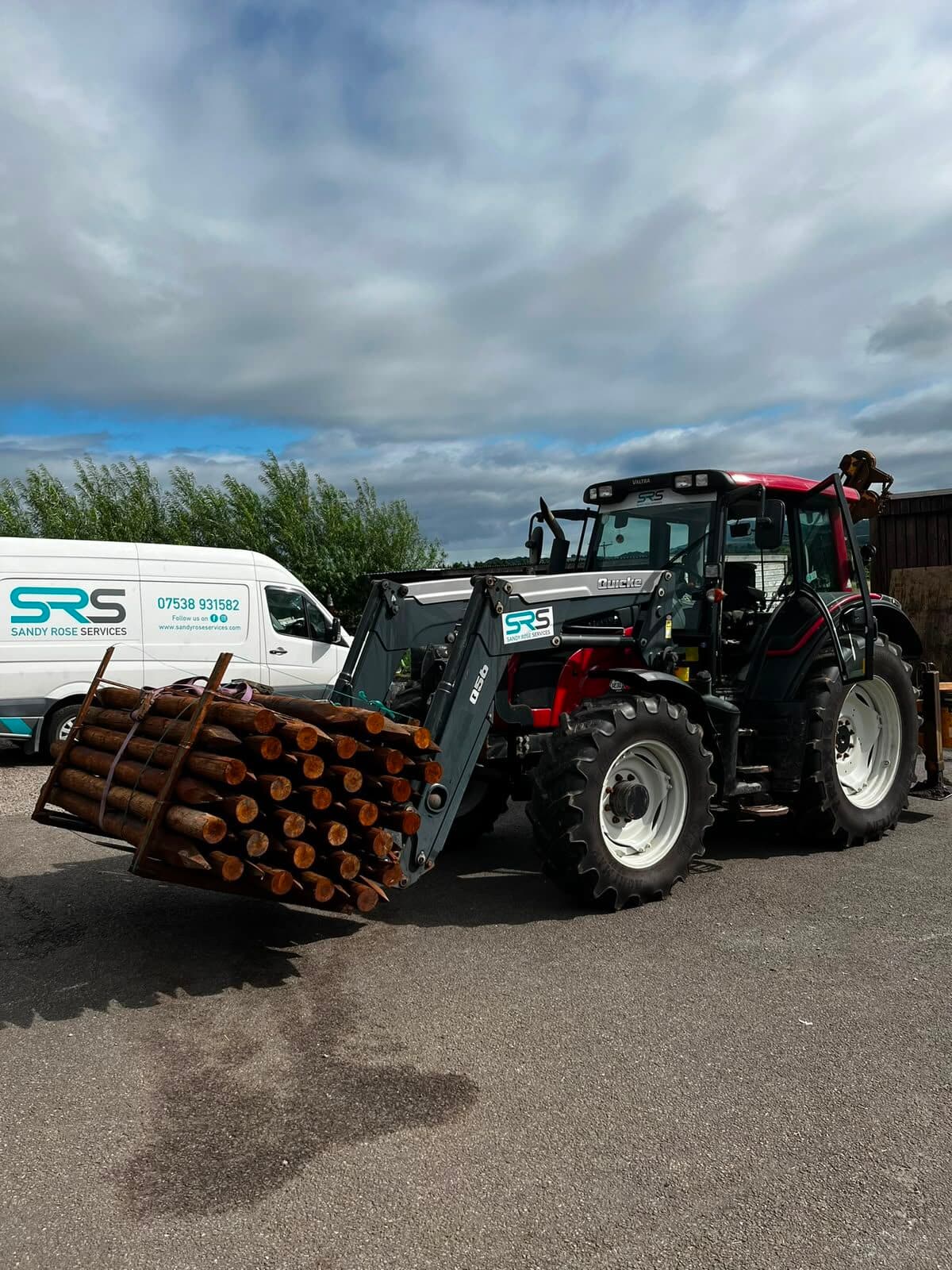 SRS-branded tractor loaded with timber fence posts