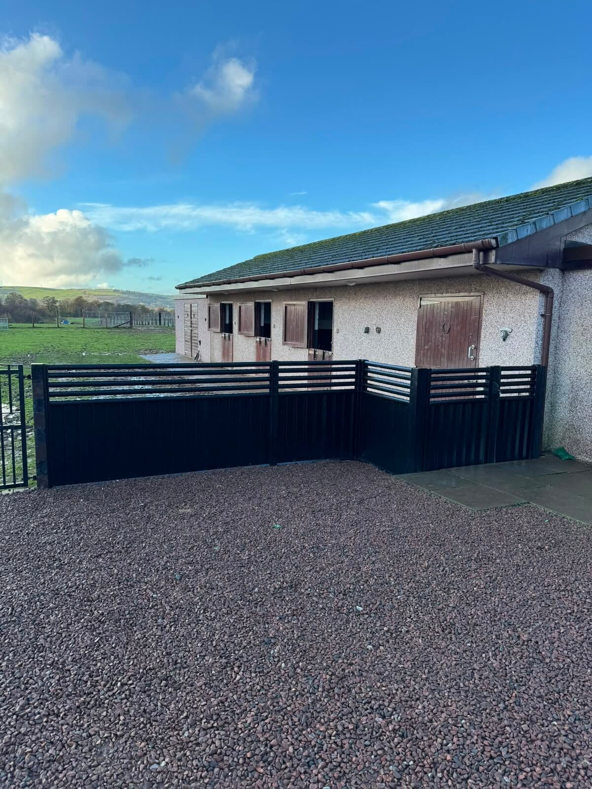 Black composite fence panels enclosing a stable yard at a private property