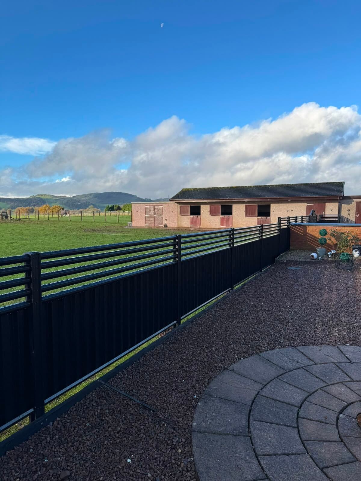 Solid composite estate fencing enclosing a stable yard and paddock